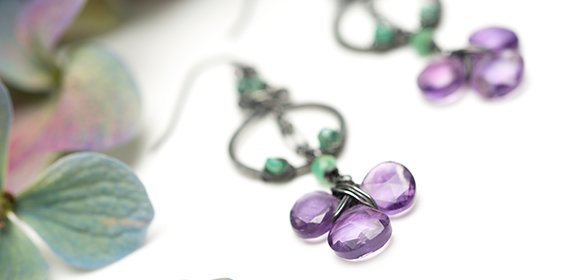 jewelry photography by Bret Corrington of violate and green leaf with purple gemstone on dangle earings on a white background