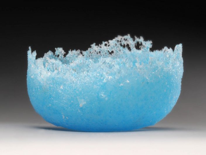 glass art photography of blue bowl with black background fading into gray foreground
